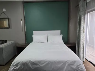 a large bed in a room with a green wall at Cuse Boutique Lodge and Conference in Polokwane