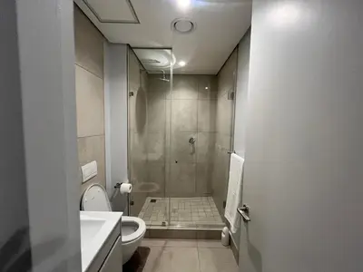 a bathroom with a shower with a toilet and a sink at The S-teemed at Ellipse in Midrand