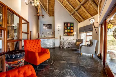 a living room with orange chairs and a counter at Kusudalweni Safari Lodge and Spa in Guernsey Nature Reserve