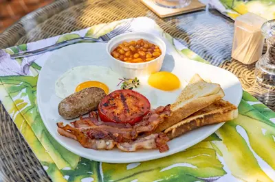 a plate of breakfast food with eggs bacon beans and toast at Kusudalweni Safari Lodge and Spa in Guernsey Nature Reserve