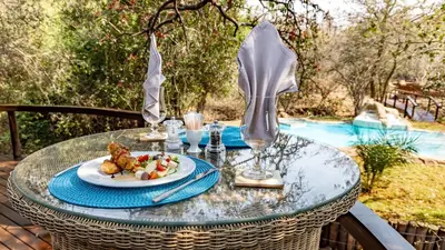 a glass table with a plate of food on it at Kusudalweni Safari Lodge and Spa in Guernsey Nature Reserve