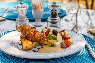 a plate of food with chicken and vegetables on a table at Kusudalweni Safari Lodge and Spa in Guernsey Nature Reserve