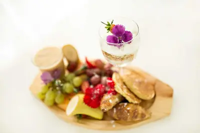 a plate of food with a glass of wine and fruit at Mavuta Boutique Apartments in Polokwane