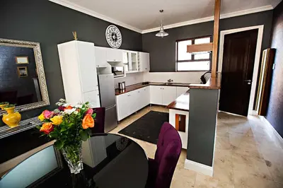 a kitchen with a vase of flowers on a glass table at Mavuta Boutique Apartments in Polokwane