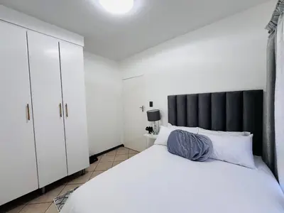 a bedroom with a large white bed with a black headboard at Rhegimel 9 in Midrand