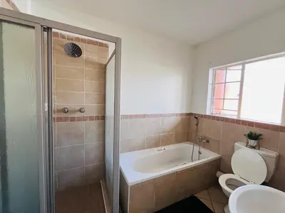 a bathroom with a tub and a toilet and a sink at Rhegimel 9 in Midrand