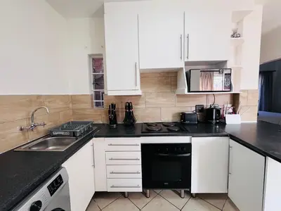 a kitchen with white cabinets and black counter tops at Rhegimel 9 in Midrand