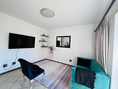 a living room with a green couch and a flat screen tv at Rhegimel 9 in Midrand
