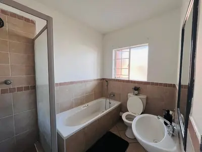 a bathroom with a tub and a toilet and a sink at Rhegimel 9 in Midrand