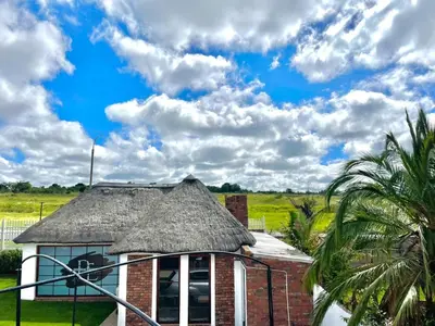 a house with a thatched roof and a palm tree at Spacious Entire place with Balcony in Kempton Park
