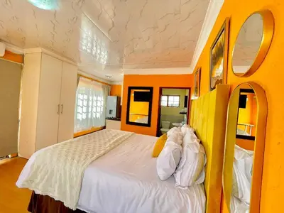 a bedroom with a large bed in an orange room at Spacious Entire place with Balcony in Kempton Park