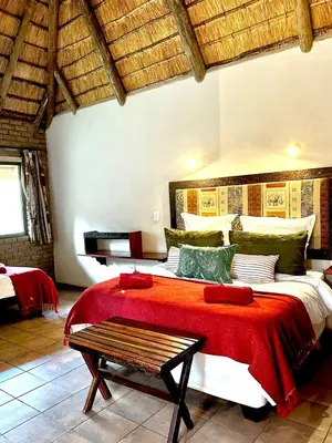 a bedroom with a large bed with a red blanket at Tshukudu Bush Camp in Hoedspruit
