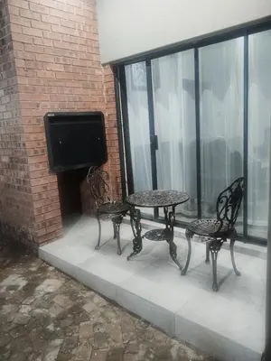 a patio with two chairs and a table and a tv at Big Mo Bev and Grill in Middelburg