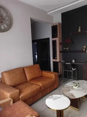 a living room with a brown couch and two tables at Big Mo Bev and Grill in Middelburg
