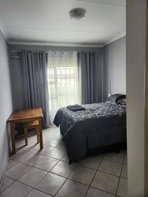 a bedroom with a bed and a table and a window at Cozy Guest House in Ermelo