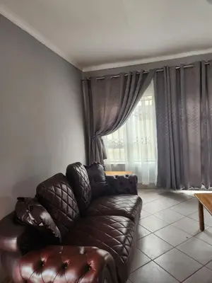 a leather couch in a living room with a window at Cozy Guest House in Ermelo