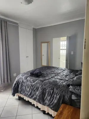 a bedroom with a bed with a black comforter at Cozy Guest House in Ermelo
