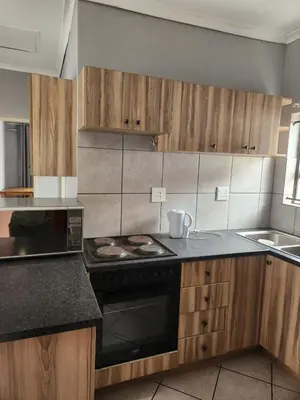 a kitchen with wooden cabinets and a stove top oven at Cozy Guest House in Ermelo