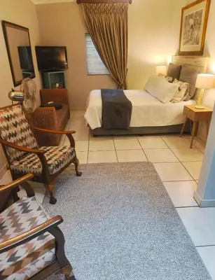 a bedroom with a bed and a chair and a couch at Peaceful Private Secure Bachelor Flat in Pretoria