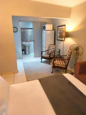 a living room with a refrigerator and a table and chairs at Peaceful Private Secure Bachelor Flat in Pretoria