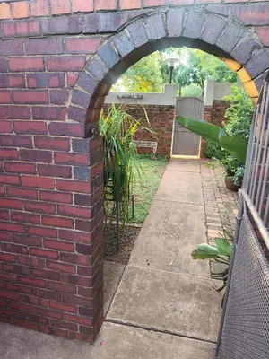 an archway in a brick wall next to a sidewalk at Peaceful Private Secure Bachelor Flat in Pretoria