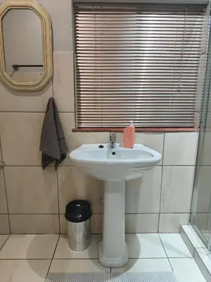 a bathroom with a white sink and a mirror at Peaceful Private Secure Bachelor Flat in Pretoria