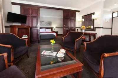 a hotel room with a bed and a coffee table at Court Classique Suite Hotel in Pretoria