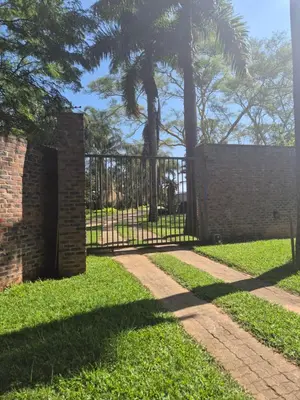 a wrought iron gate in a park with palm trees at The Macadamia Nut Farm House in White River