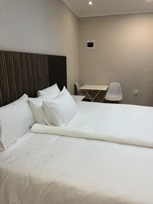 a bedroom with a large bed with white sheets and pillows at Petron home in Kempton Park
