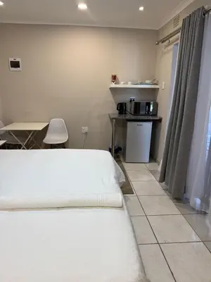 a bedroom with two beds and a table and a kitchen at Petron home in Kempton Park