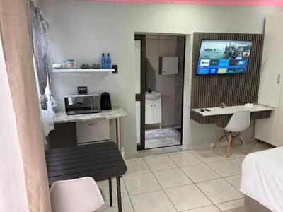 a room with a bed and a kitchen with a microwave at Petron home in Kempton Park