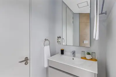 a white bathroom with a sink and a mirror at 4316 Ellipse luxury Apartment, Waterfall in Midrand