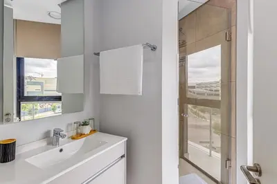 a white bathroom with a sink and a shower at 4316 Ellipse luxury Apartment, Waterfall in Midrand