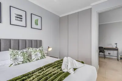a white bedroom with a bed and a desk at 4316 Ellipse luxury Apartment, Waterfall in Midrand