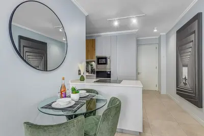 a dining room with a glass table and chairs and a mirror at 4316 Ellipse luxury Apartment, Waterfall in Midrand