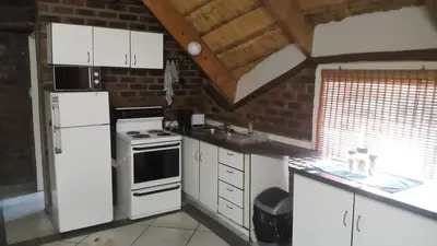 a kitchen with white appliances and a brick wall at Do Drop In in Hoedspruit