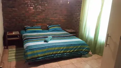 a bed in a room with a brick wall at Do Drop In in Hoedspruit