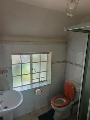 a bathroom with a toilet and a sink and a window at Do Drop In in Hoedspruit