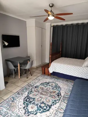 a bedroom with a bed and a table and a ceiling fan at 899 On Burlington in Pretoria