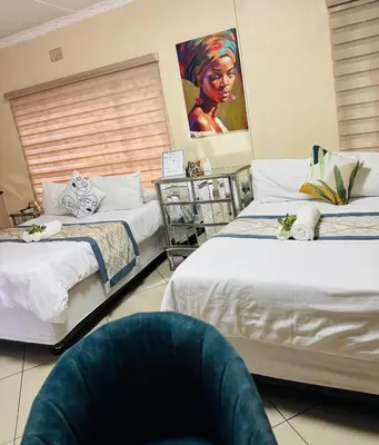 a bedroom with two beds and a painting on the wall at C-Rane Lodge B in Phalaborwa
