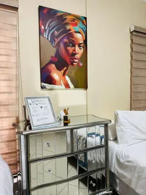a glass table in a bedroom with a painting on the wall at C-Rane Lodge B in Phalaborwa