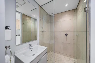 a white bathroom with a shower and a sink at Skyline Serenity in Midrand