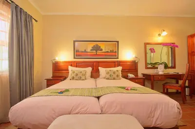 a bedroom with a bed with two pillows and a desk at Tzaneen Country Lodge in Tzaneen