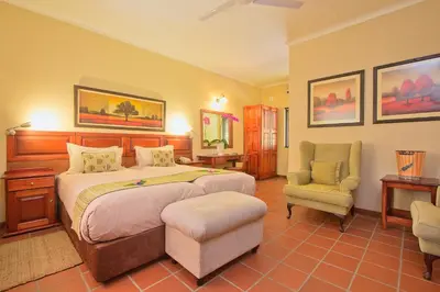 a bedroom with a large bed and a chair at Tzaneen Country Lodge in Tzaneen