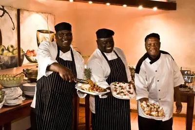 three chefs standing in a kitchen holding plates of food at Tzaneen Country Lodge in Tzaneen