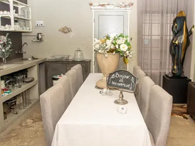 a table with chairs and a vase with flowers on it at Muckleneuk Manor in Pretoria
