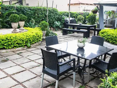 a patio with a table and chairs and bushes at Muckleneuk Manor in Pretoria