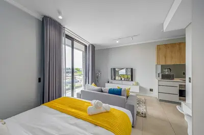 a bedroom with a bed and a living room at Golden Sun Suites in Midrand