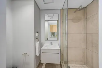 a white bathroom with a sink and a shower at Golden Sun Suites in Midrand