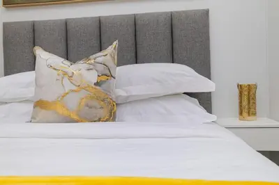 a bed with white sheets and pillows at Golden Sun Suites in Midrand